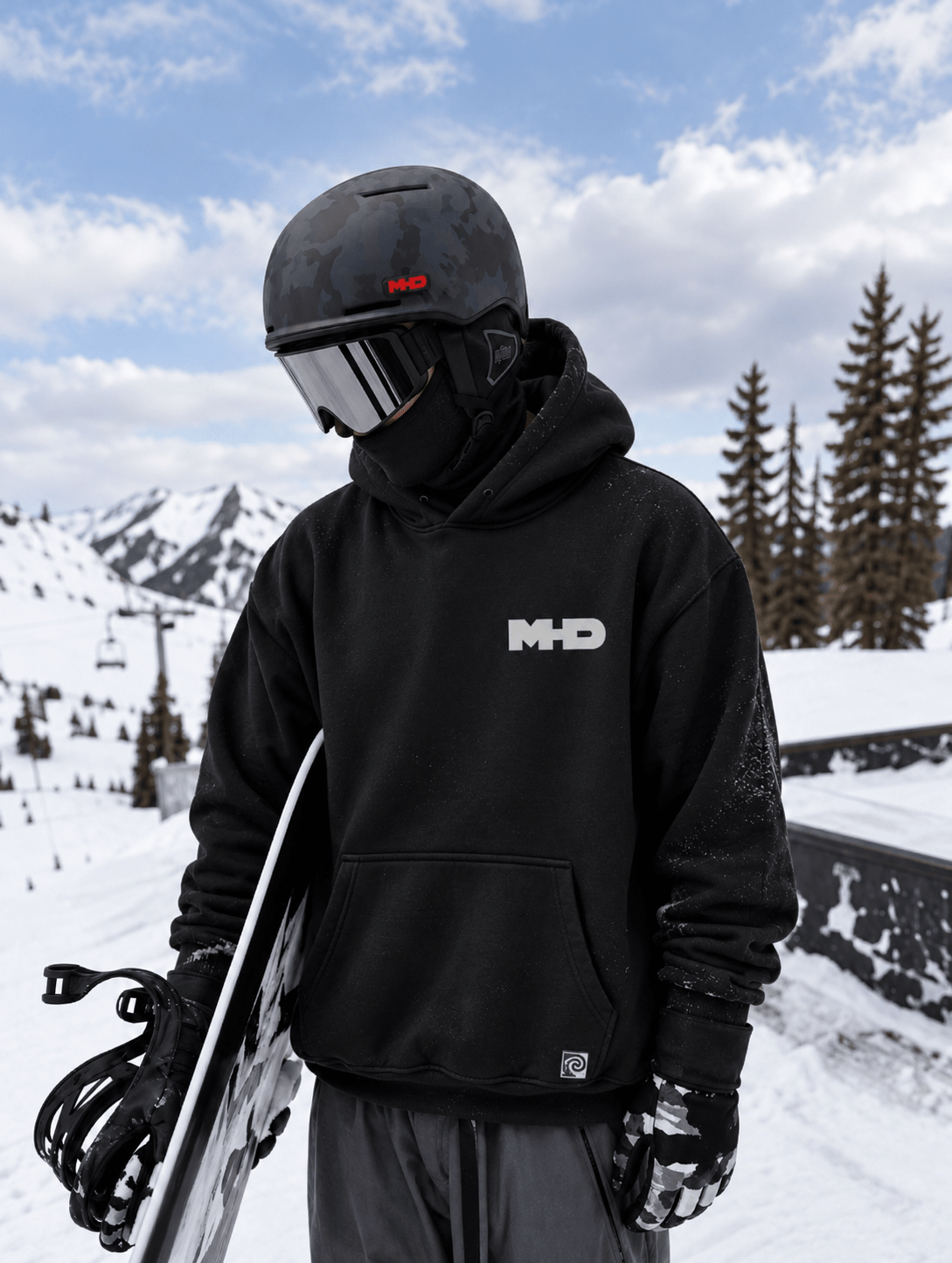 A snowboarder wearing a black hoodie with a white 'M&D' logo on the chest, 