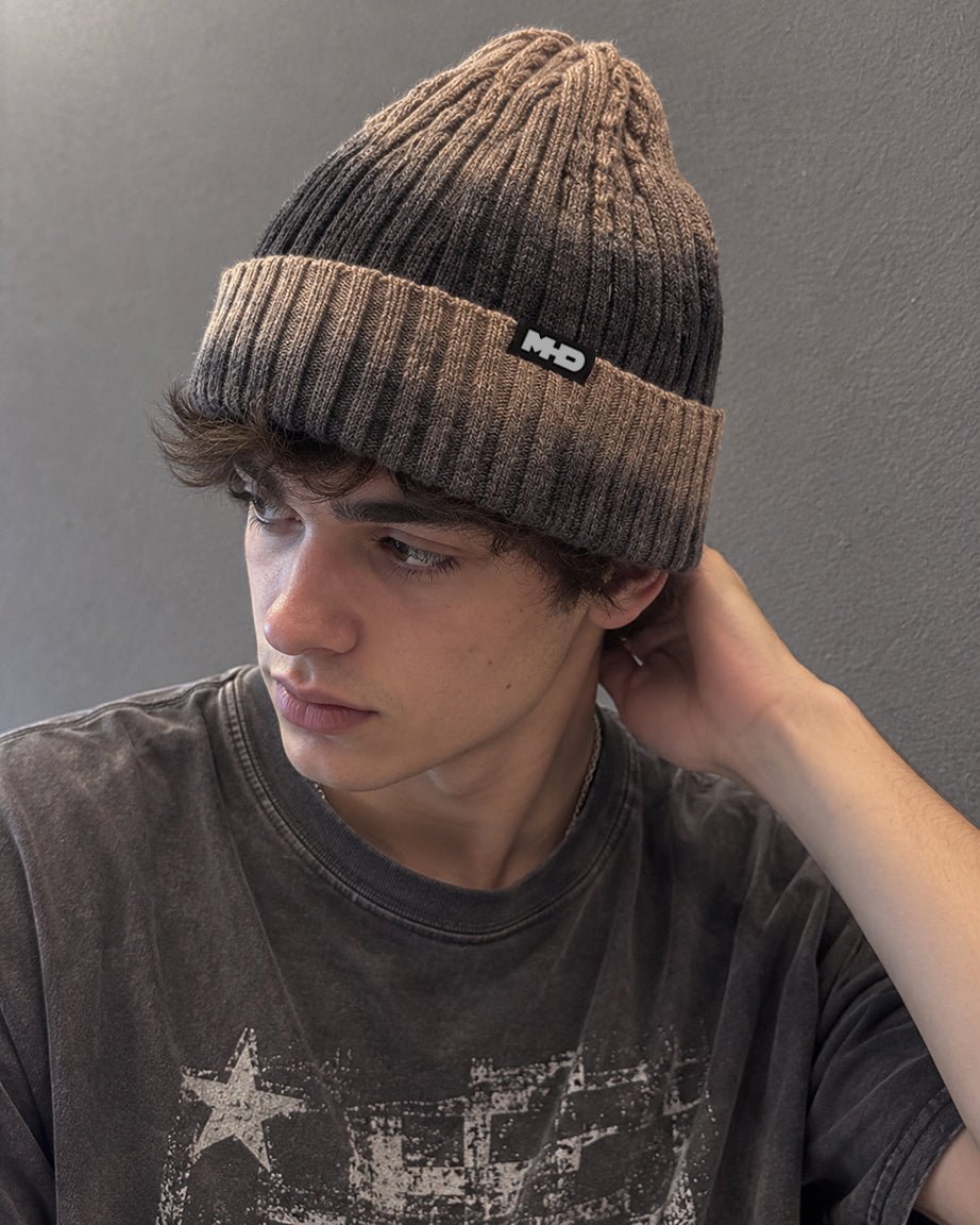 A young man wearing a dark brown and black gradient ribbed knit MHD beanie 