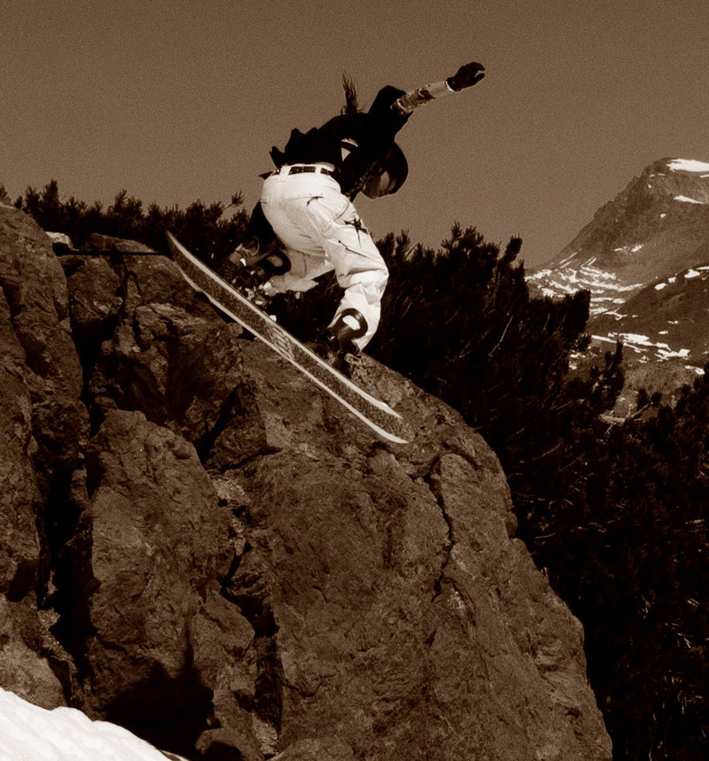 Snowboarder jumping off a cliff wearing DUSTY snow gear by MHD